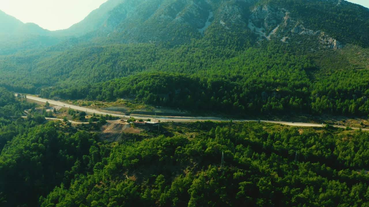 鸟瞰上方的乡村公路通过树木繁茂的山脉。视频素材