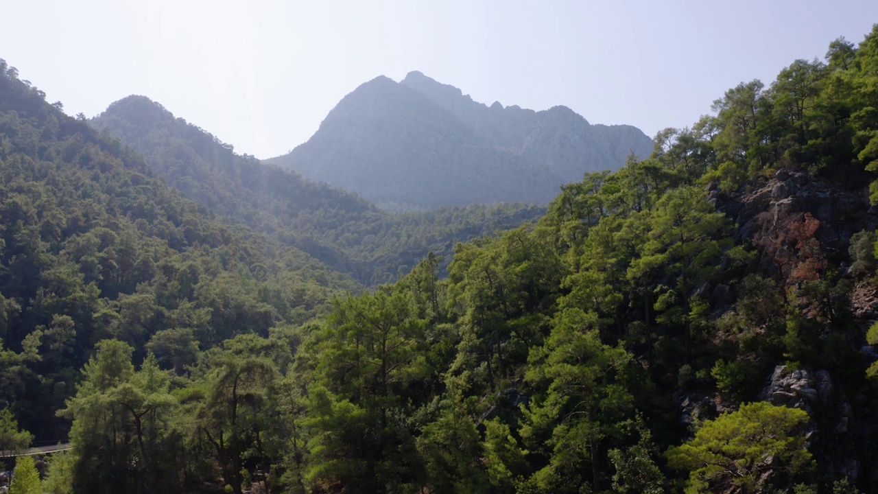 在蓝天的映衬下，山峰上长满了绿色茂密的森林。视频素材