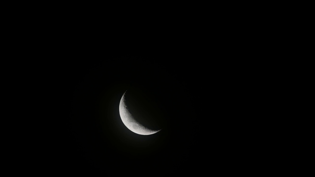 风把云吹过新月。夜空中有一弯新月和许多星星。视频素材