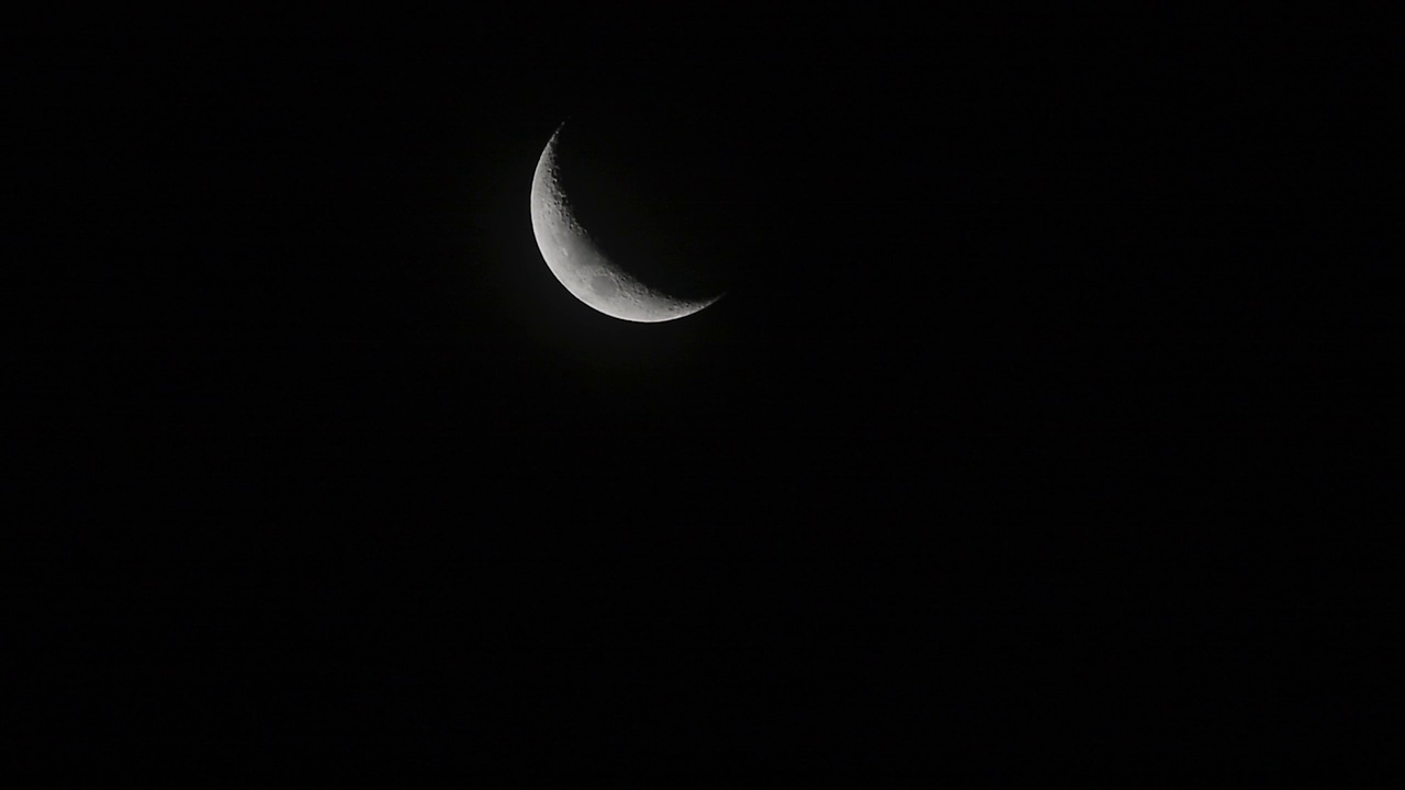 风把云吹过新月。夜空中有一弯新月和许多星星。视频素材