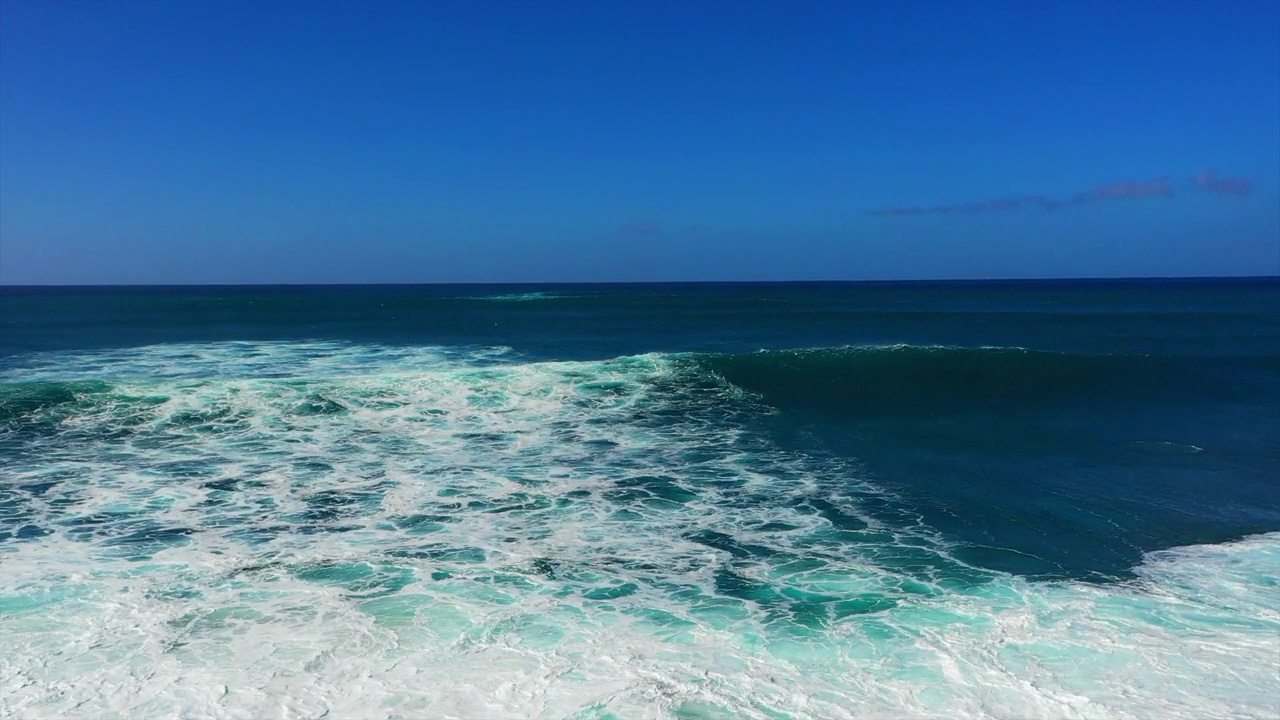 空中前进拍摄美丽的海浪在蓝色的海洋与天空在阳光灿烂的一天-夏威夷威基基视频素材