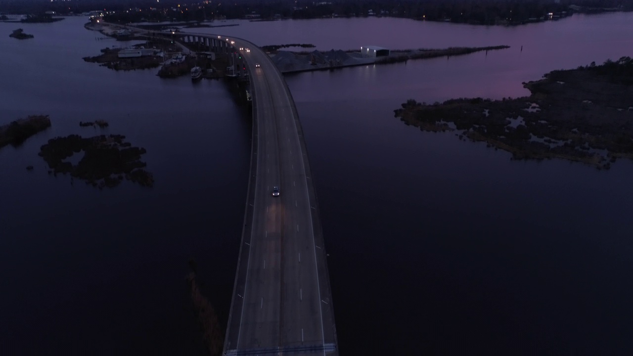 空中倾斜向下拍摄的照明汽车移动在著名的桥梁道路上湖在黄昏-新奥尔良，路易斯安那州视频素材