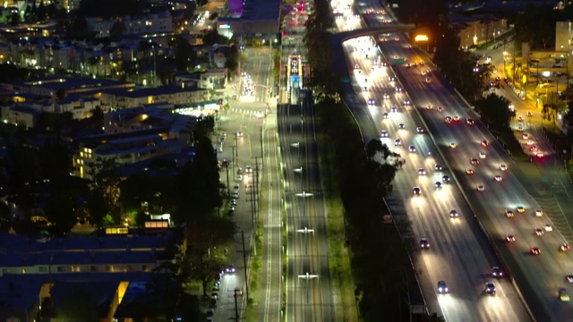 空中倾斜向下拍摄的汽车在公路上的铁路轨道，无人机在城市在夜间向后飞行-卡尔弗城，加利福尼亚视频素材