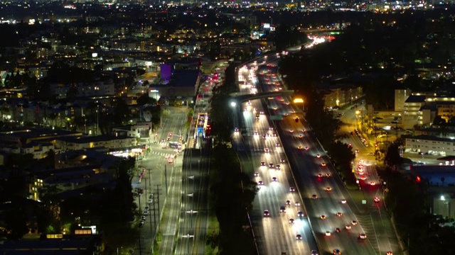 空中向后倾斜向下拍摄的照明汽车移动在城市的夜晚-卡尔弗城，加利福尼亚视频素材