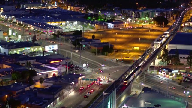 空中向前倾斜向上拍摄地铁在夜间照亮的城市轨道上移动-卡尔弗城，加利福尼亚视频素材