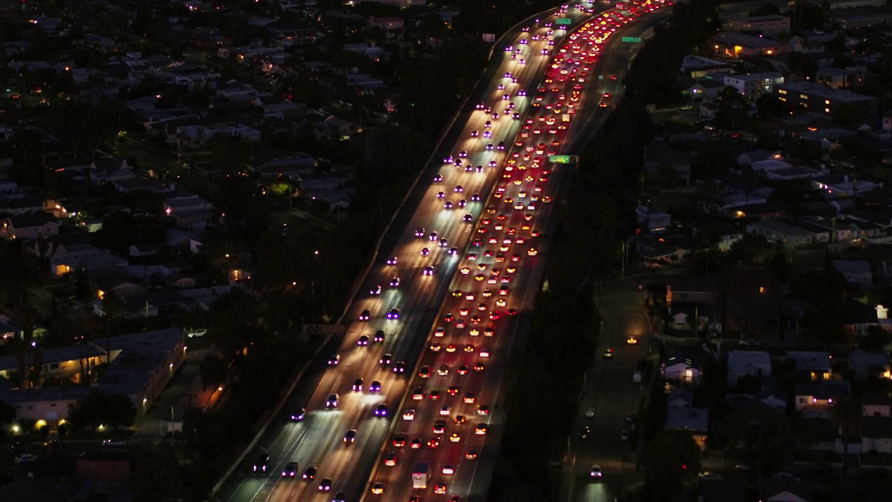 空中向后拍摄的照明汽车在夜间在住宅之间的道路上移动-卡尔弗城，加利福尼亚视频素材