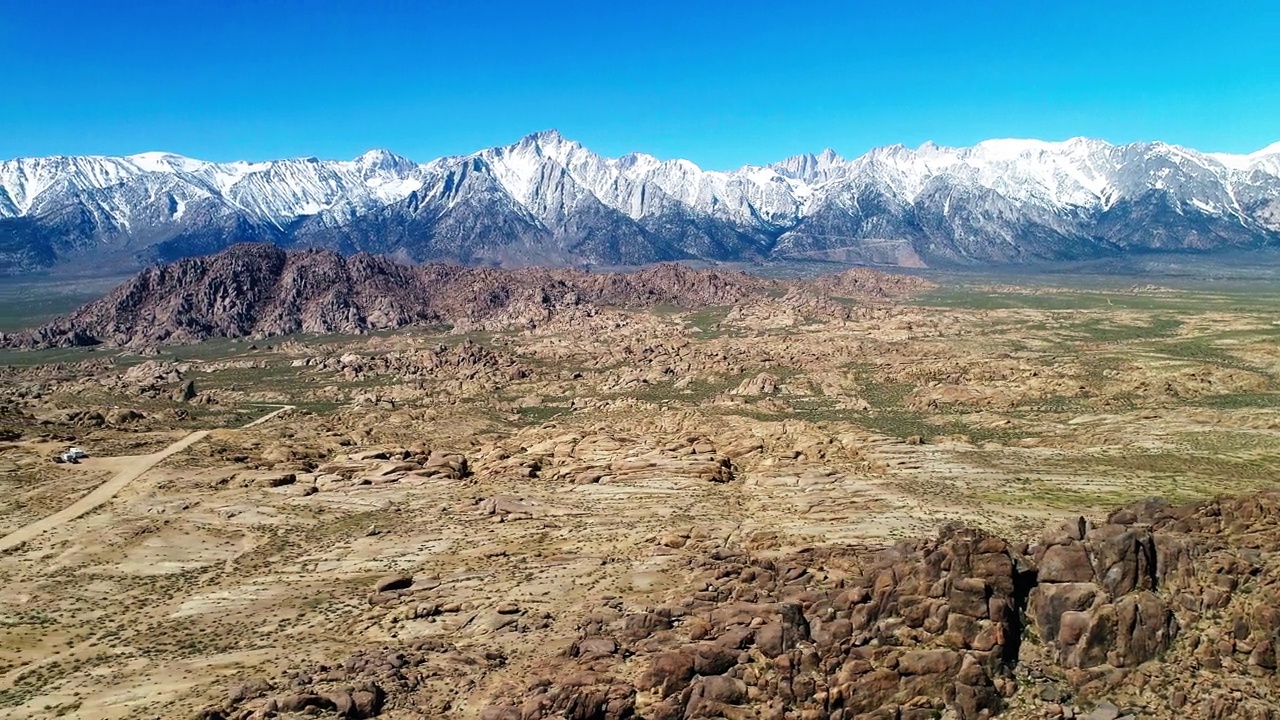 空中平移风景雪山山脉反对晴空，无人机在晴天飞越半干旱沙漠-大松树，加利福尼亚视频素材