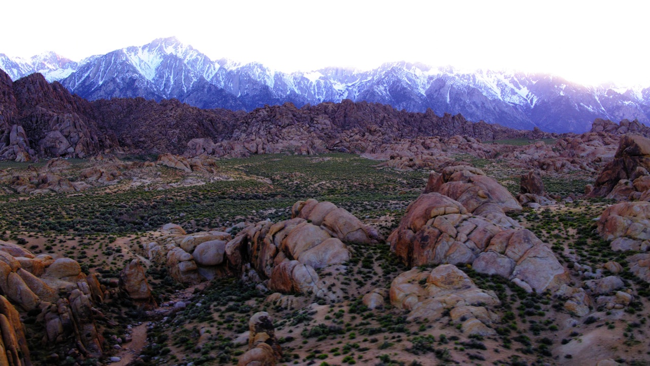 空中平移拍摄的岩石形成的景观对雪山在沙漠地区- Sierra县，加利福尼亚视频素材