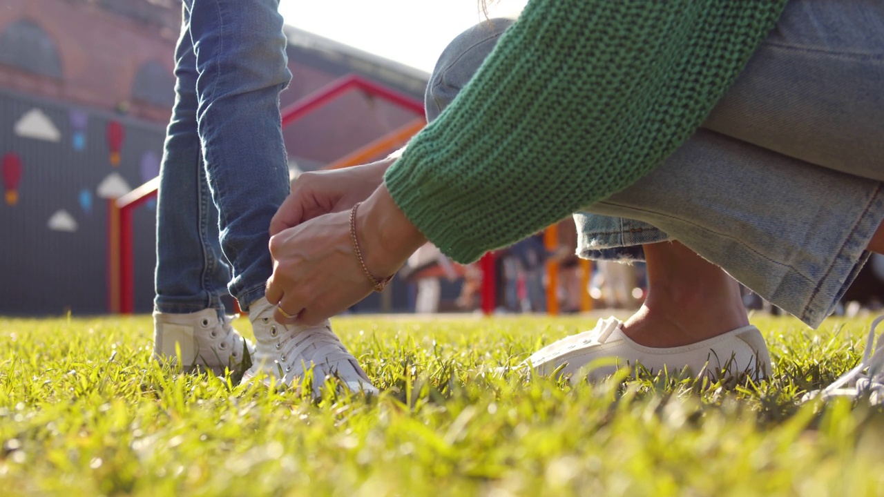 近距离的慈爱的母亲帮助小男孩穿鞋在公园。实时视频素材