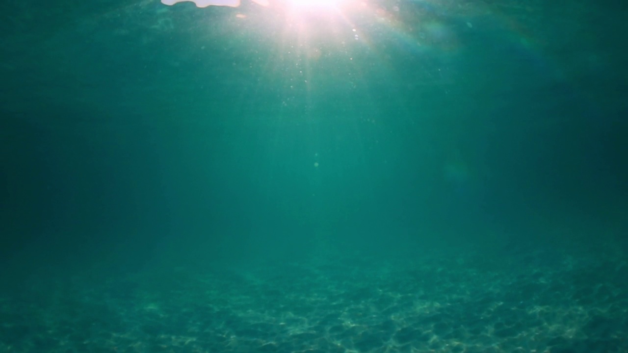 阳光穿透海水，带着柔和的波浪和运动，在沙滩上形成的水下光纹视频素材