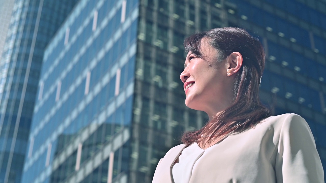 穿西装的女人正抬头看着城市建筑视频素材