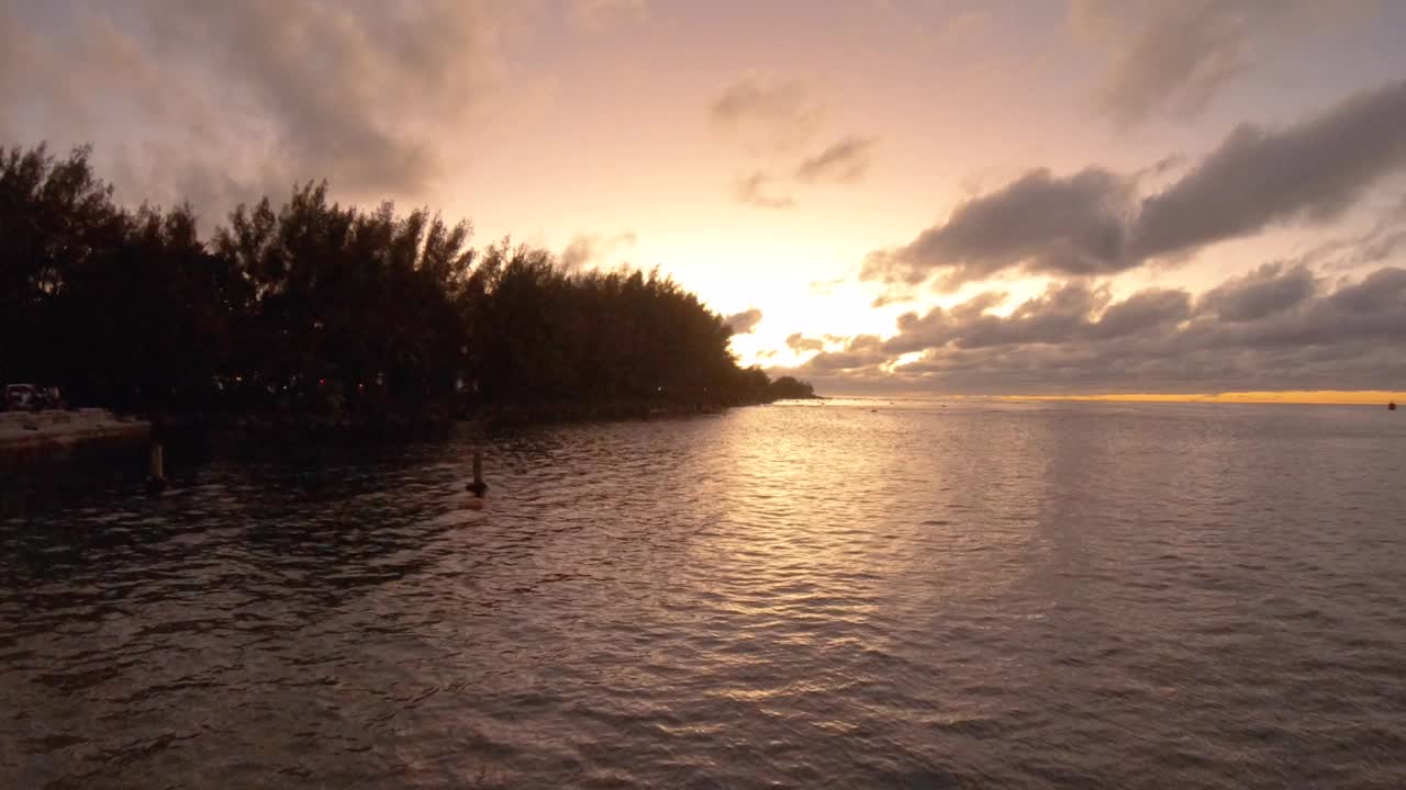 水平静止的海洋海岸线海湾沙质岩石海滩与椰子树看向北太平洋地平线在橙色日落与交通旁边的泻湖和平蛤水波视频素材