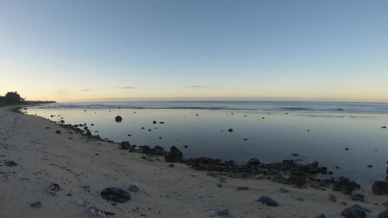 手持静止的海洋海岸线海湾沙质岩石海滩和椰子树，在日落黎明时分，在泻湖和平蛤水波内，眺望东太平洋的地平线视频素材