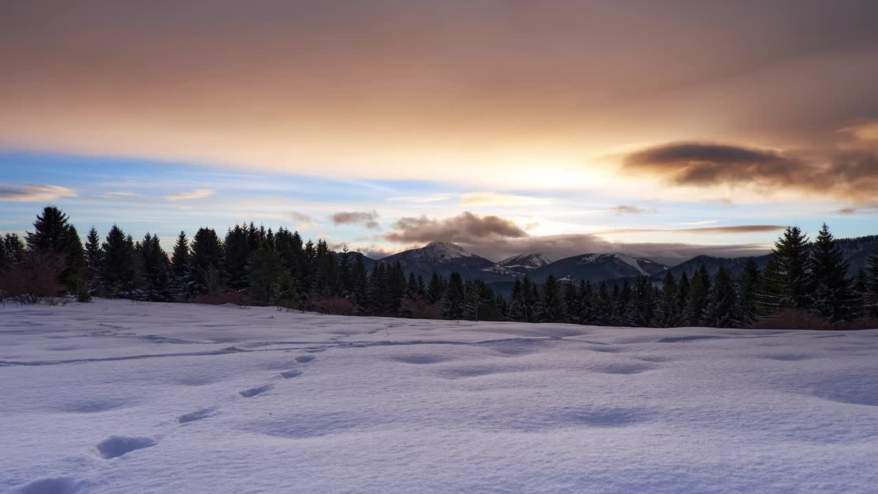 冬天的山景在黄昏时被白雪覆盖。雪地里有猎物的脚印。FHD间隔拍摄视频素材