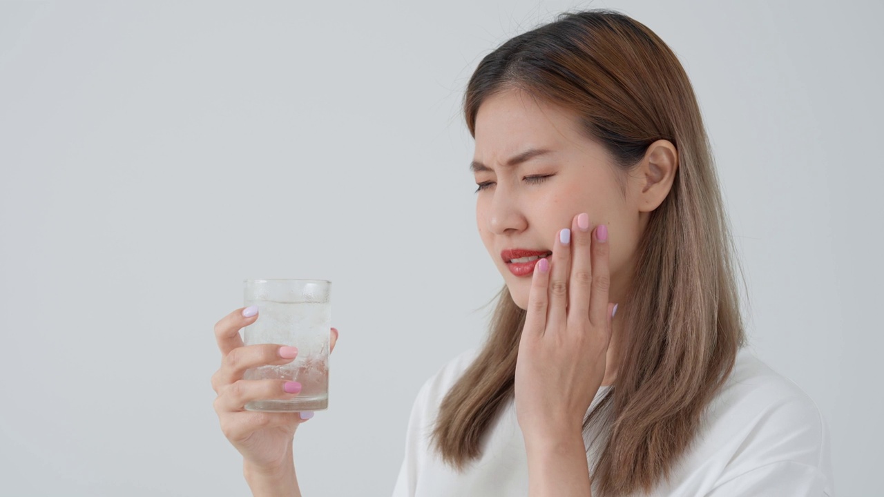 亚洲女性喝冷饮后感觉牙齿敏感，女性患牙、蛀牙问题，牙科护理，拔牙、蛀牙问题，口臭，牙龈萎缩，口腔卫生指导视频素材