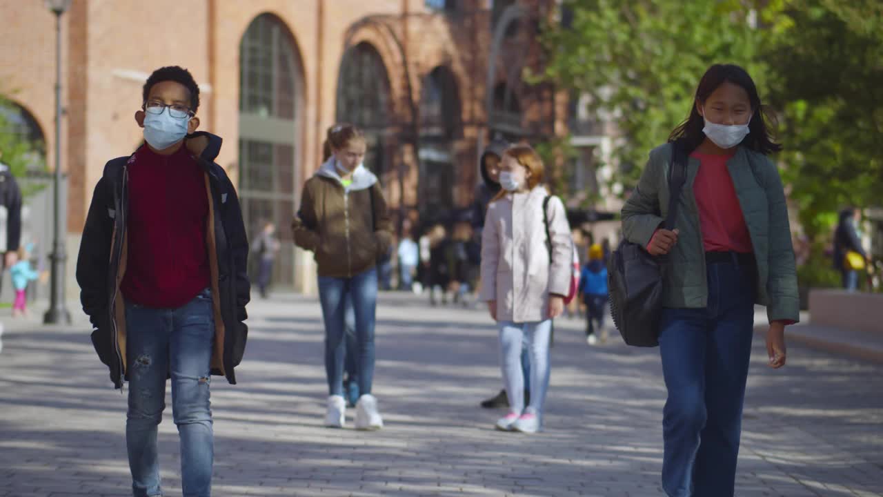 戴着医用口罩的学生离开学校。实时视频素材