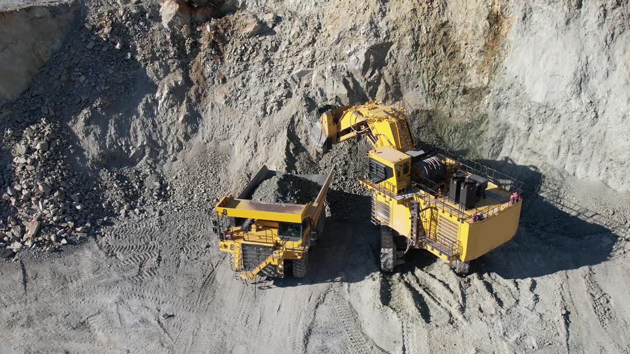 用自卸车装载岩石，大型采石场卡车从露天矿山运输矿石，慢动作鸟瞰图视频素材