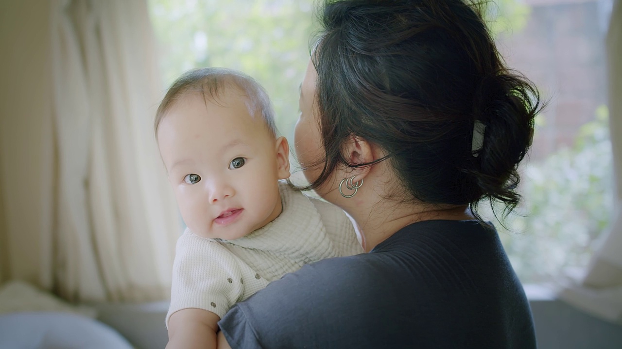 近距离肖像年轻妈妈抱抱抱抱小女婴可爱的小婴儿学步，可爱的亚洲妈妈抱抱小婴儿孩子，放松享受温柔的家庭时刻母性概念视频素材