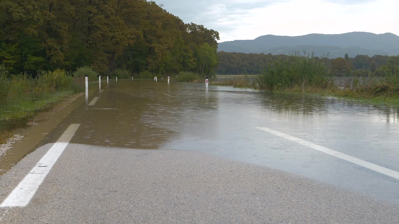 河水溢出了堤岸，淹没了农村的一段柏油路视频素材