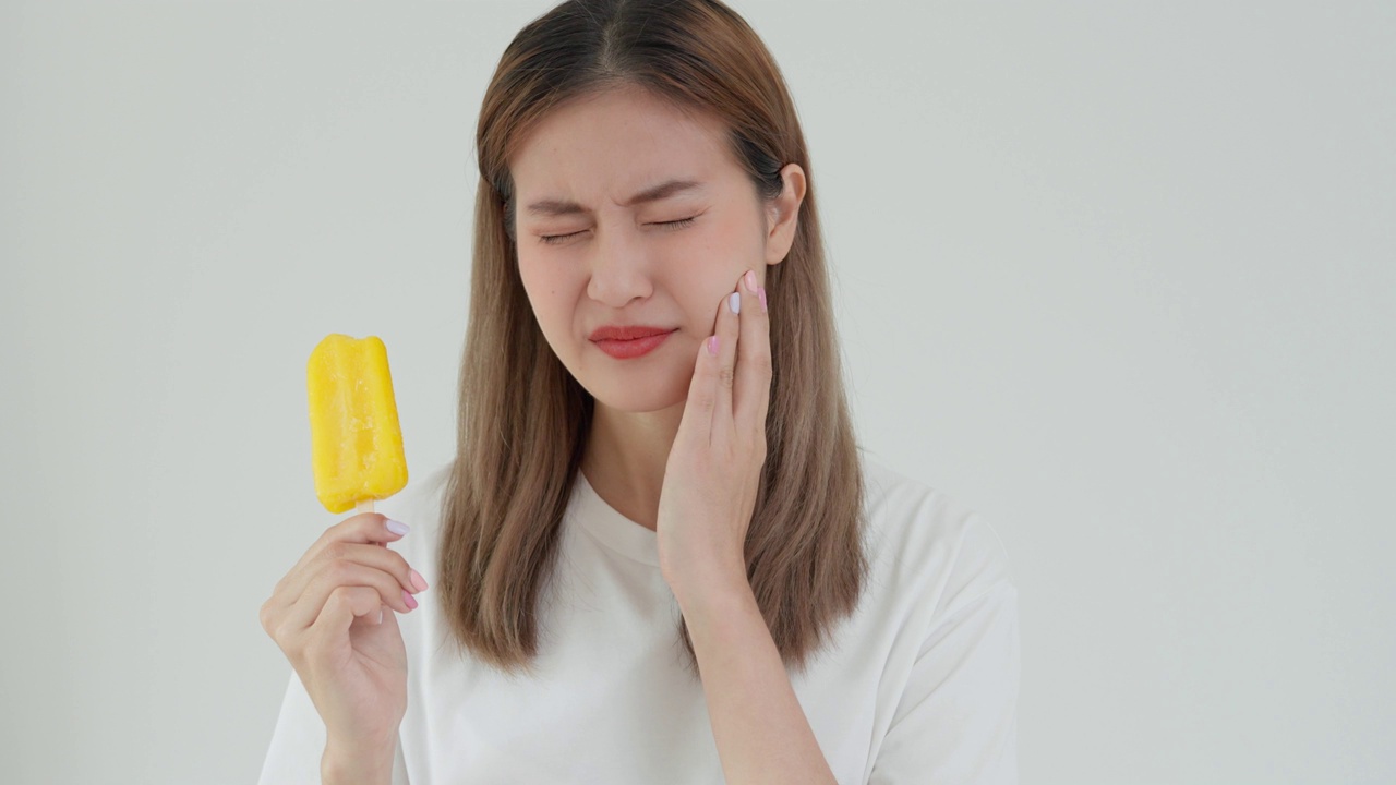 亚洲女性在吃完冰淇淋后感到牙齿敏感，女性遭受牙齿、蛀牙问题、牙科护理、拔牙、蛀牙问题、口臭、牙龈衰退、口腔卫生指导视频素材