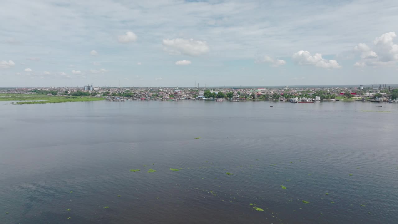 空中拍摄的住宅建筑在云层下的景观，无人机在阳光灿烂的日子里飞过涟漪河-伊基托斯，秘鲁视频素材