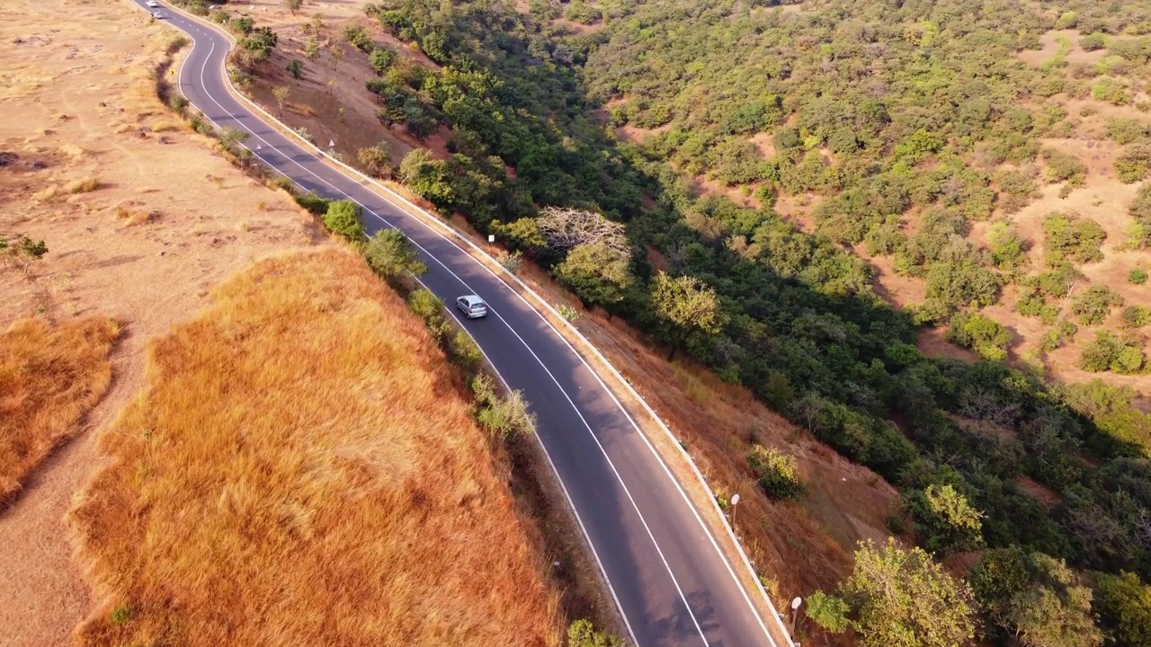 鸟瞰一条美丽的弯曲道路，它穿过一侧的山谷，降落在另一侧视频素材