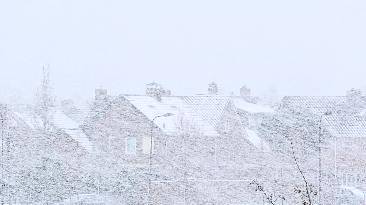 欧洲小房子屋顶上的大雪街道上被雪覆盖的房子和树木。视频下载