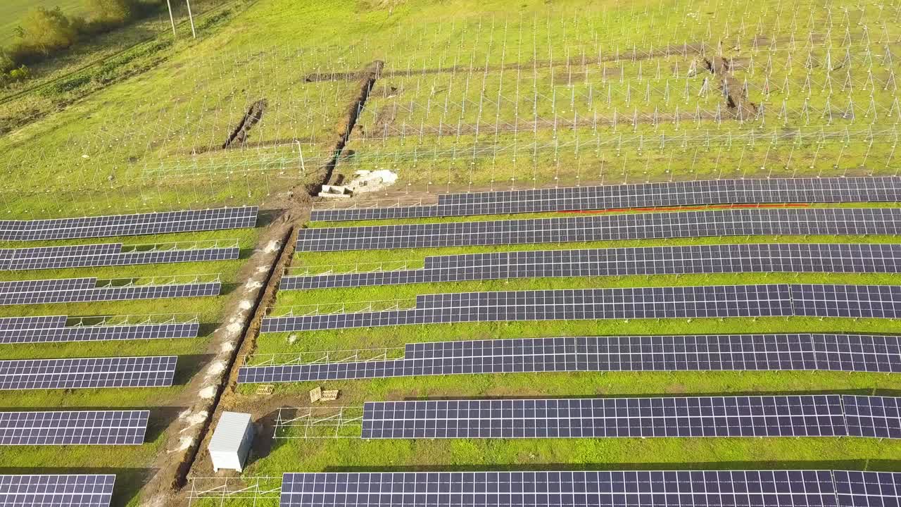 绿色土地上正在建设的太阳能发电厂鸟瞰图。用于生产清洁生态能源的电板组装。视频素材