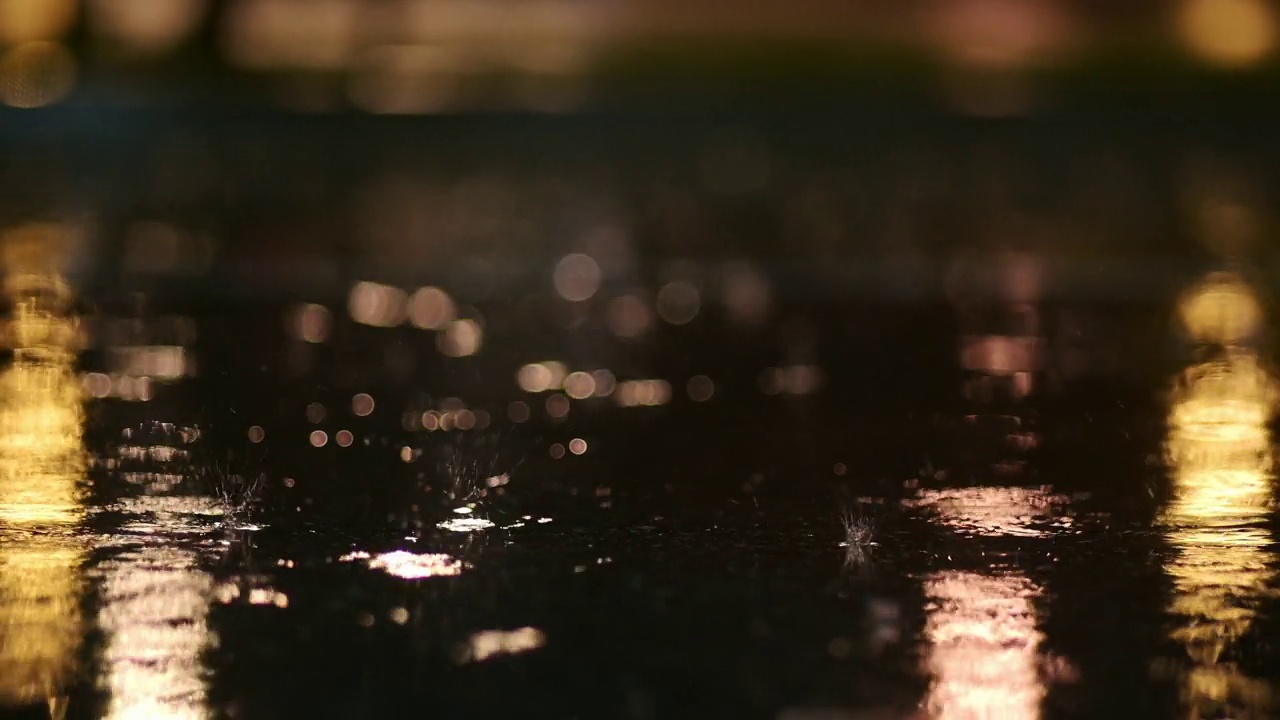 夜间城市暴雨的大气视频。从低处拍摄的大雨和水坑。视频素材