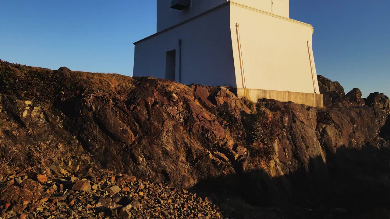 在海洋和灯塔附近茂密的森林和岩石海岸上空飞行视频素材