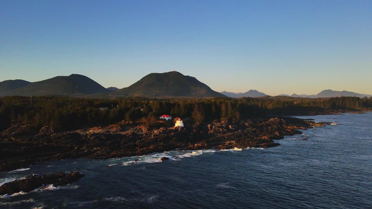 在海洋和灯塔附近茂密的森林和岩石海岸上空飞行视频素材