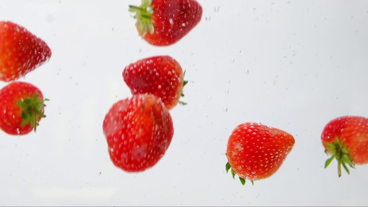 慢镜头，一群草莓在水下移动，美味的甜点，近景。视频素材