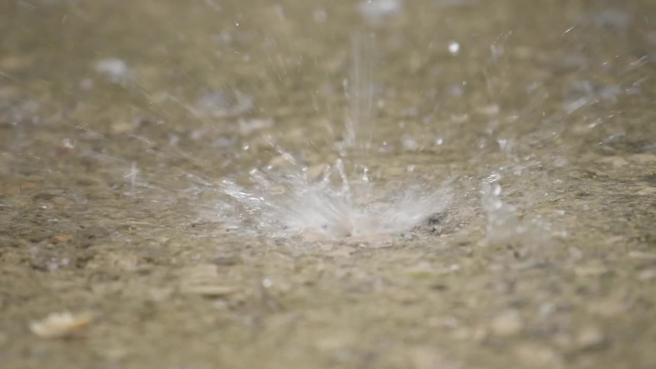 夏天，雨滴溅在水泥人行道上视频素材