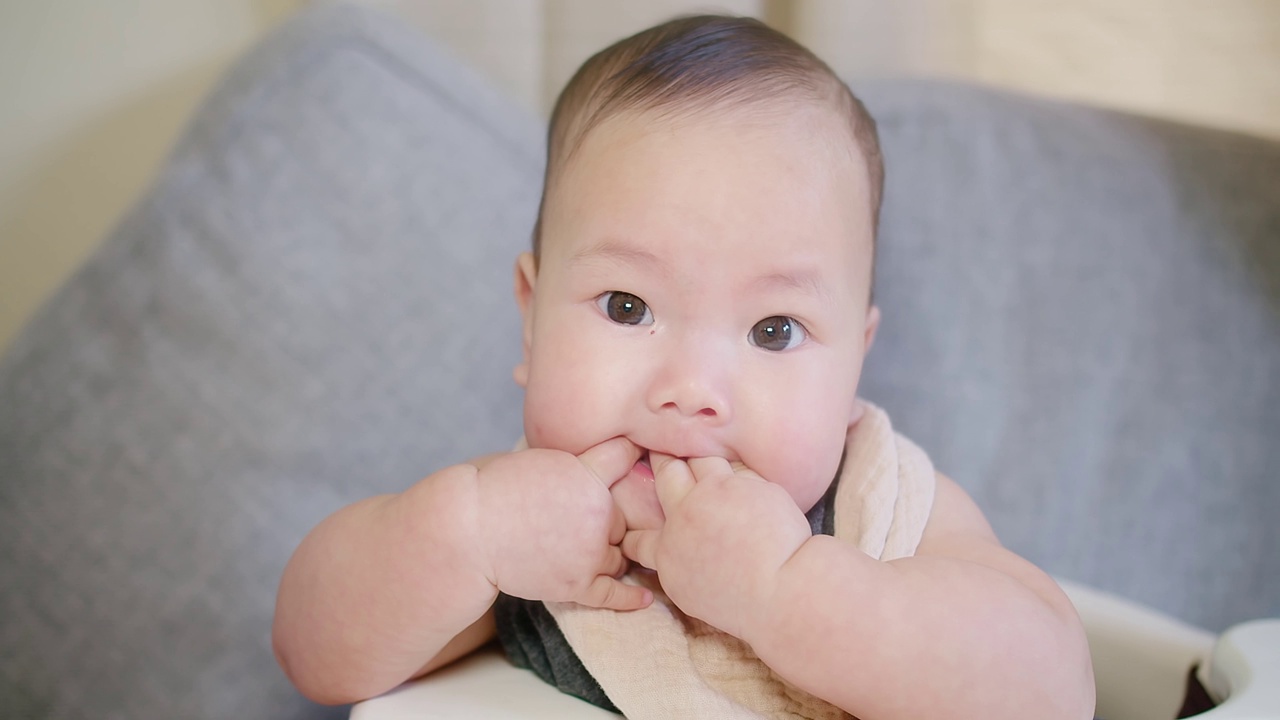 肖像接近快乐的人可爱的小可爱的亚洲新生儿婴儿婴儿儿童蹒跚学步的脸室内家，天真的表情可爱的女孩孩子看着相机视频素材