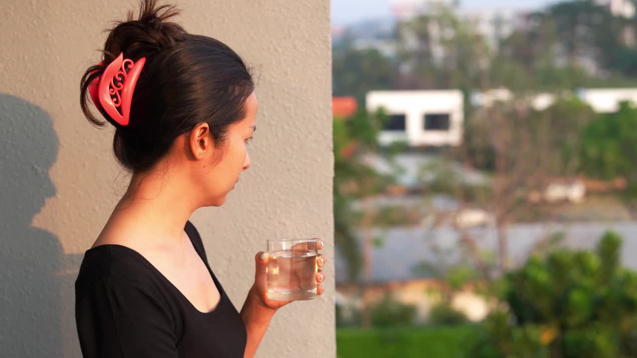 女人在家里用玻璃杯喝淡水。视频素材