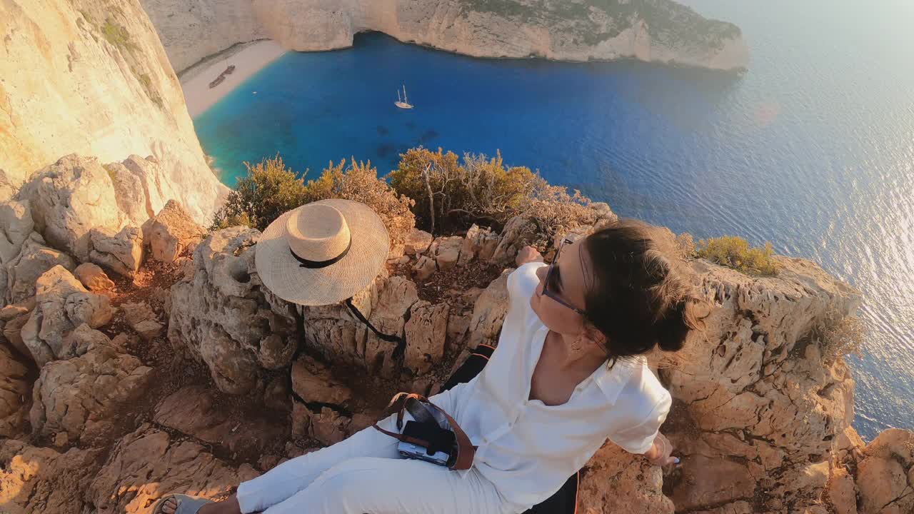 年轻女子在日落时看着赞特纳瓦吉奥海滩沉船的风景。希腊爱奥尼亚海扎金索斯岛的泻湖视频素材