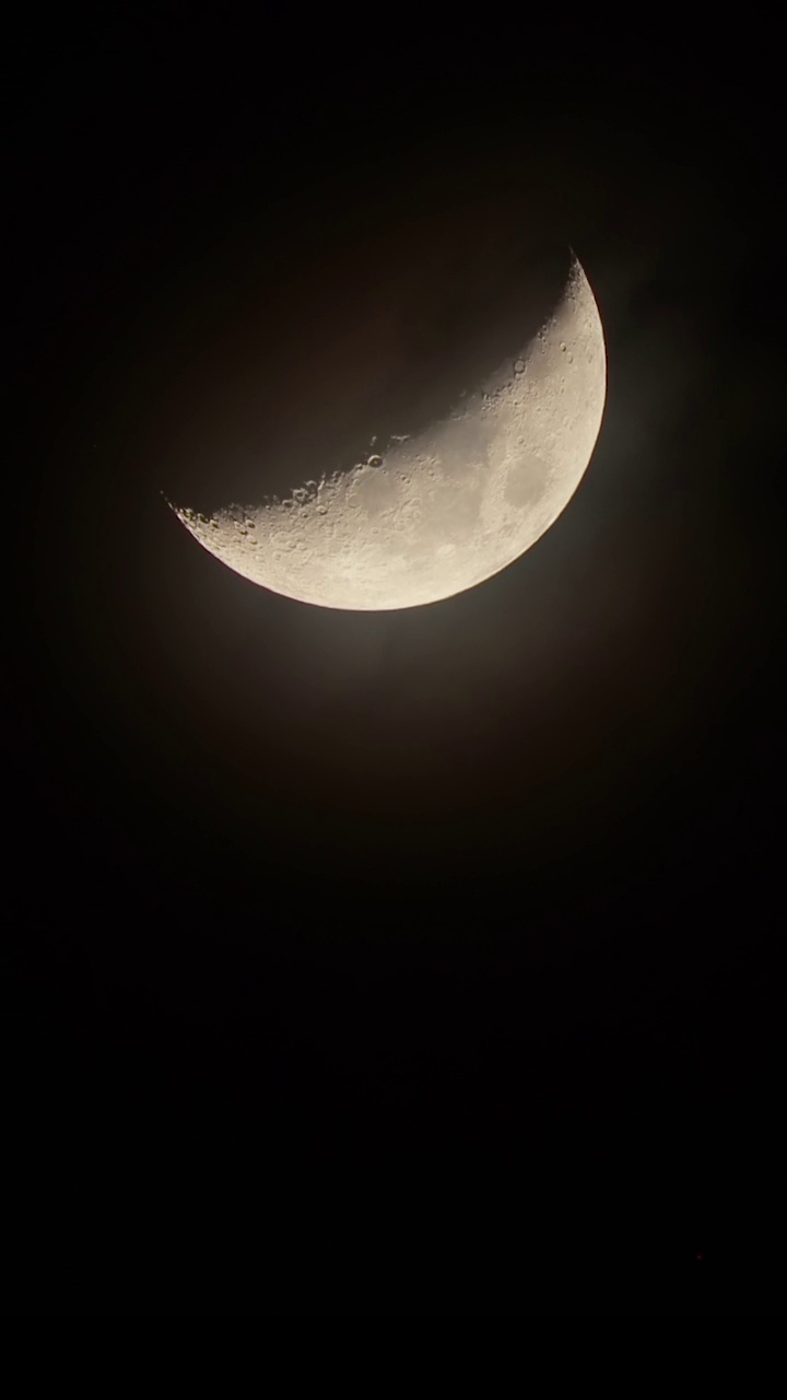 生长阶段的月亮在夜空中特写。云在月牙前飞舞视频素材