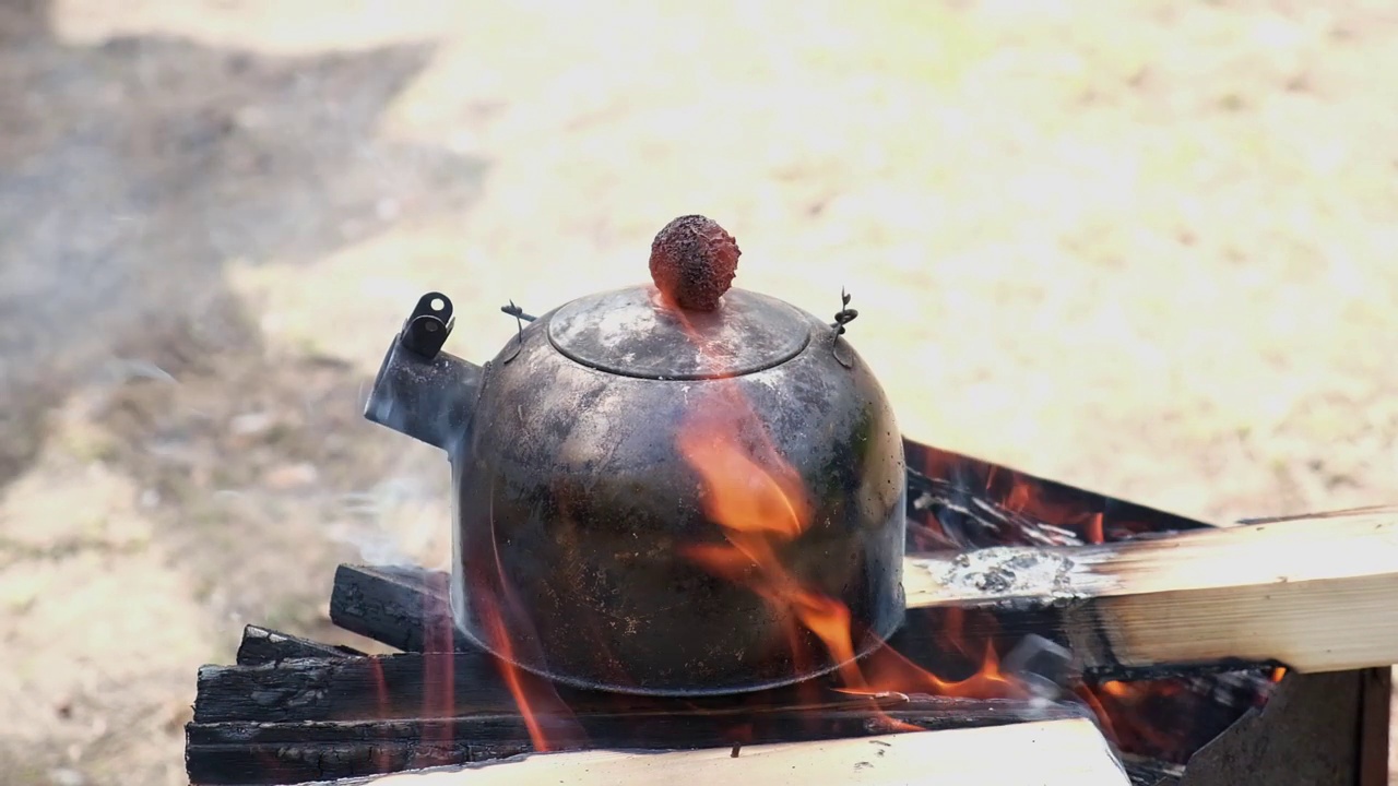 竞选中火上浇油。徒步旅行的茶派对。一壶乌黑的水在营火上沸腾。视频素材