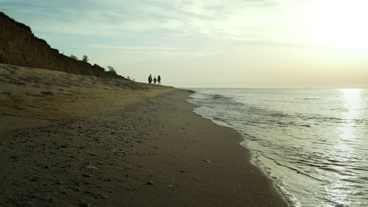 一家人在海边沙滩散步。海浪拍打着海岸。视频素材