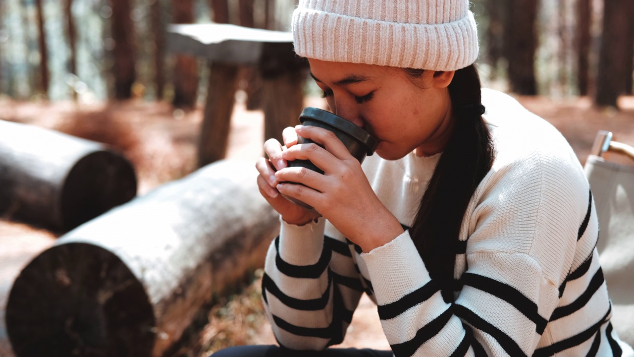 迷人的亚洲年轻女子露营者享受早上的咖啡和自然景观在森林中。露营的概念视频素材