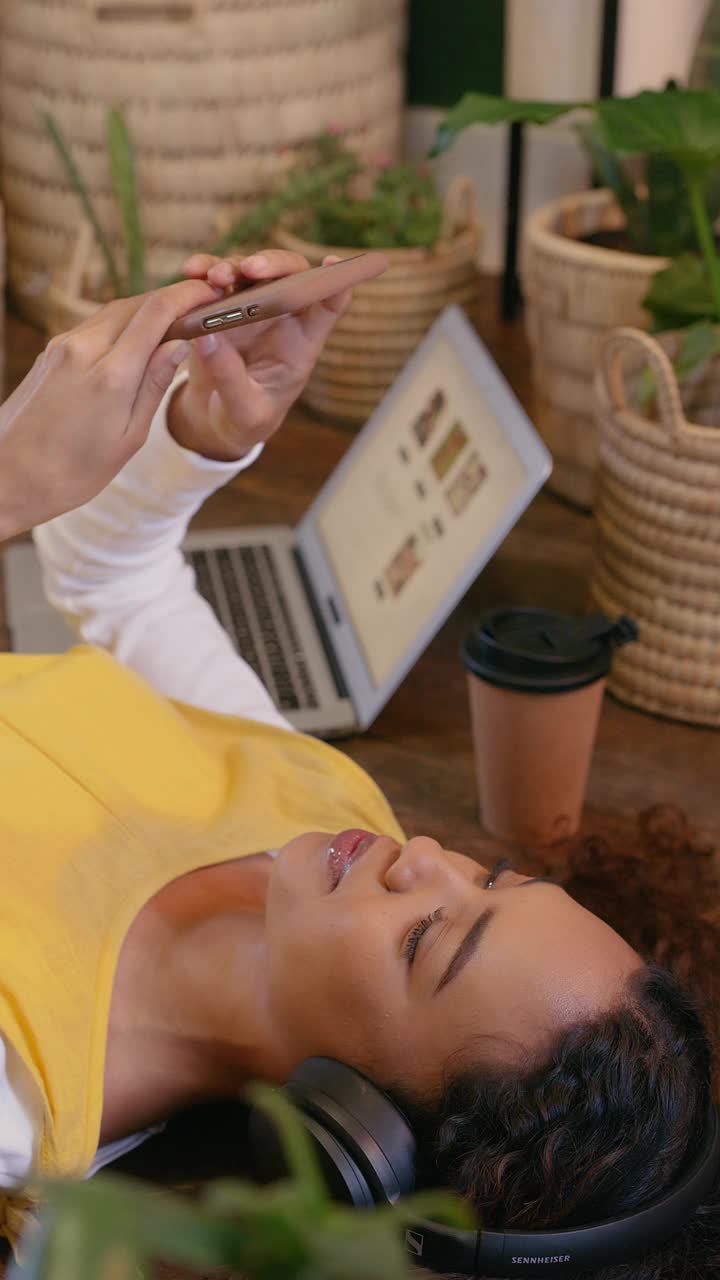 植物，电话和耳机的女人放松在地板上的心理健康，健康播客和平静的互联网博客。禅宗，和平和年轻人与音乐流媒体应用程序在波西米亚或生态友好的房间视频素材