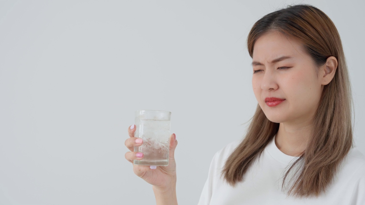 亚洲女性喝冷饮后感觉牙齿敏感，女性患牙、蛀牙问题，牙科护理，拔牙、蛀牙问题，口臭，牙龈萎缩，口腔卫生指导视频素材