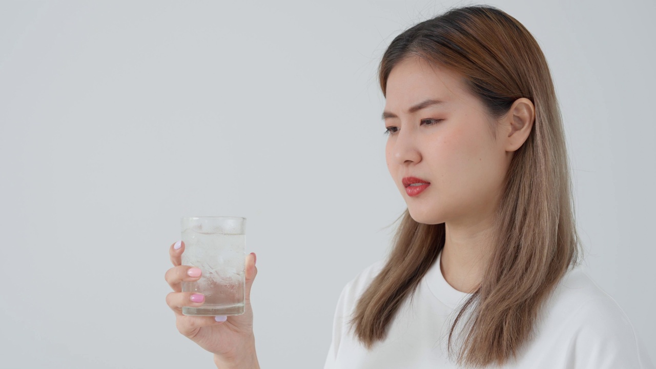 亚洲女性喝冷饮后感觉牙齿敏感，女性患牙、蛀牙问题，牙科护理，拔牙、蛀牙问题，口臭，牙龈萎缩，口腔卫生指导视频素材