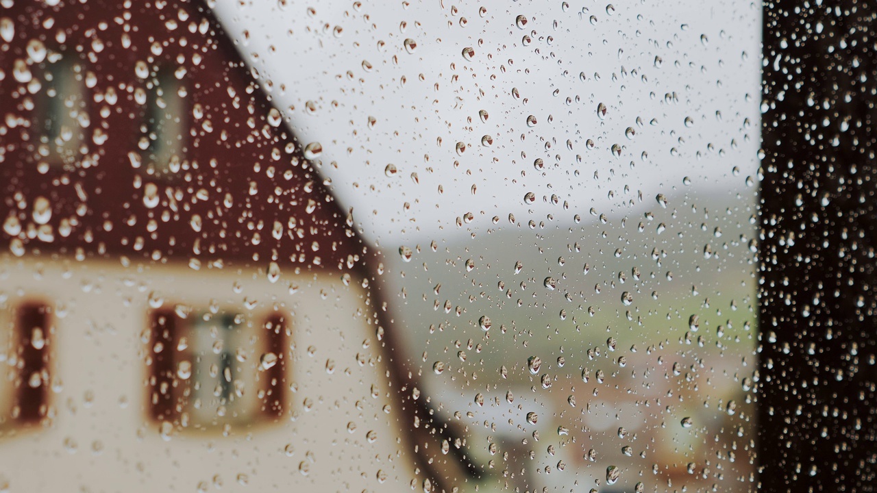 雨滴倾泻在窗户玻璃上，模糊的乡村背景视频素材