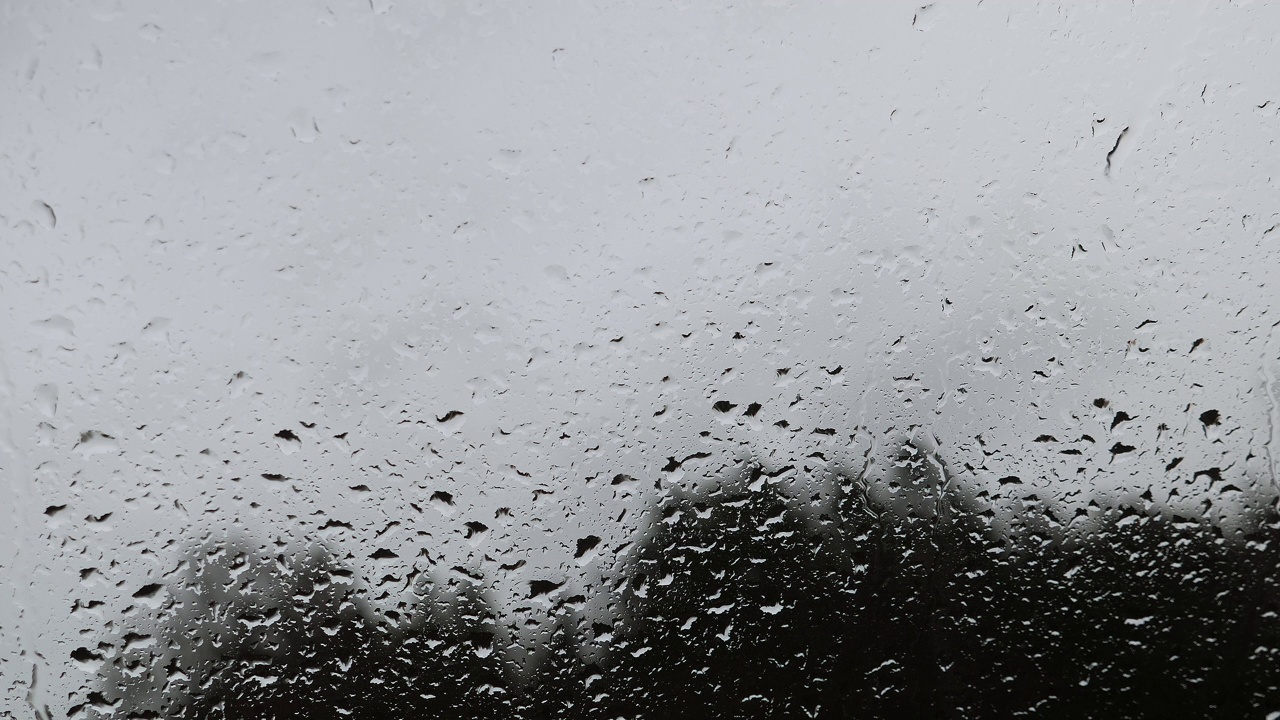 雨滴落在窗玻璃上。雨天，水滴在玻璃窗上滑动视频素材