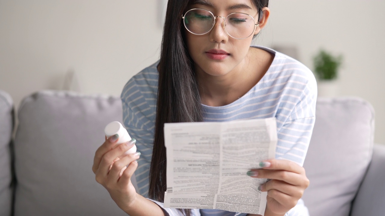 年轻的亚洲妇女在服药前阅读医嘱。视频素材