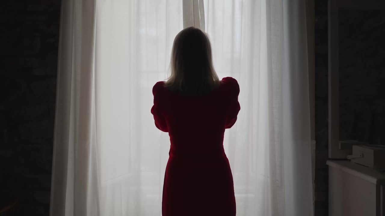 一个女人在她的公寓里拉开窗帘。视频素材