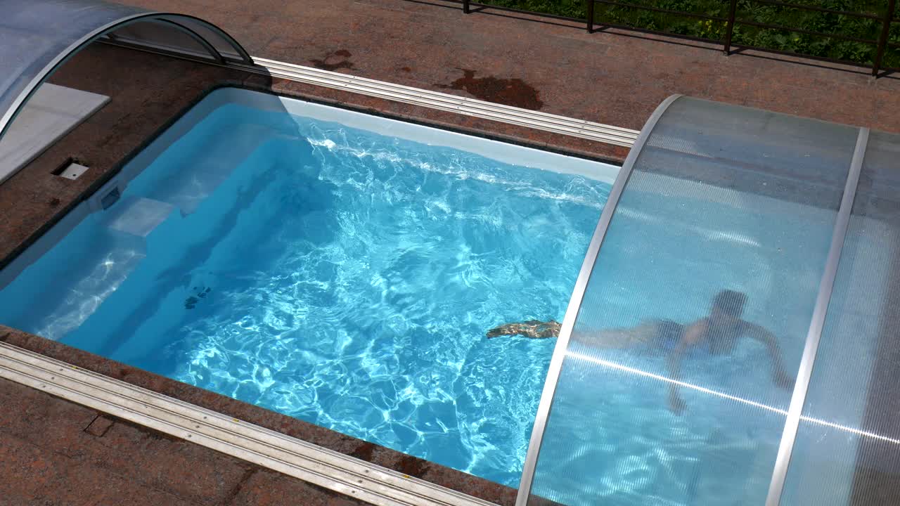 一名年轻女子漂浮在蓝色水池的水面下。视频下载