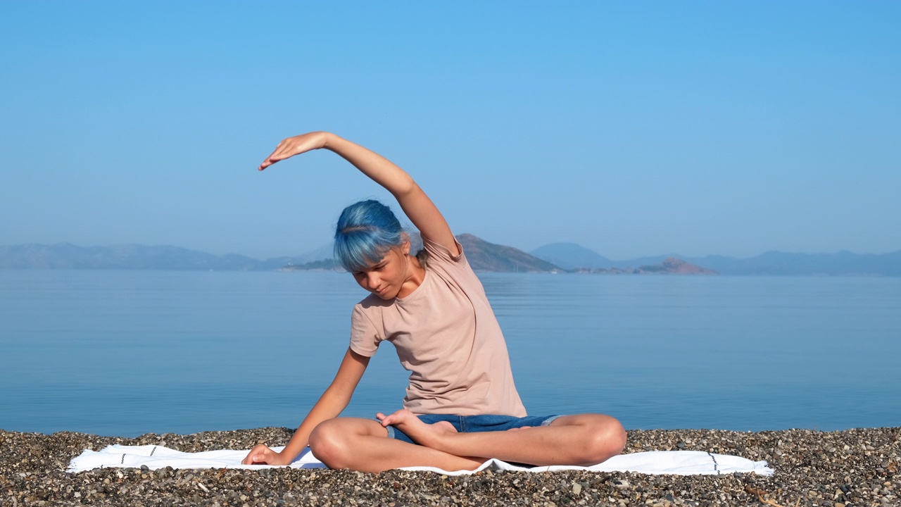 青少年在岸上伸展莲花瑜伽。视频素材