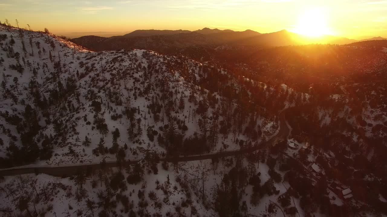 夕阳映照着冰雪覆盖的高山和松林，航拍加州向前视频素材